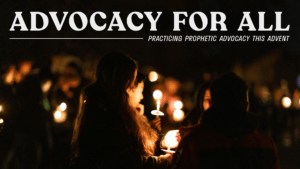 People holding candles during an evening worship service, symbolizing communal hope and prophetic advocacy during Advent.