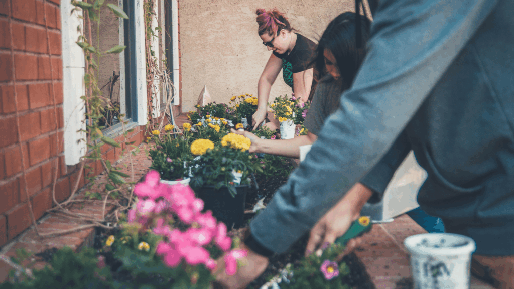 Volunteers planting flowers together in a community garden, representing faith-based advocacy and collective action.