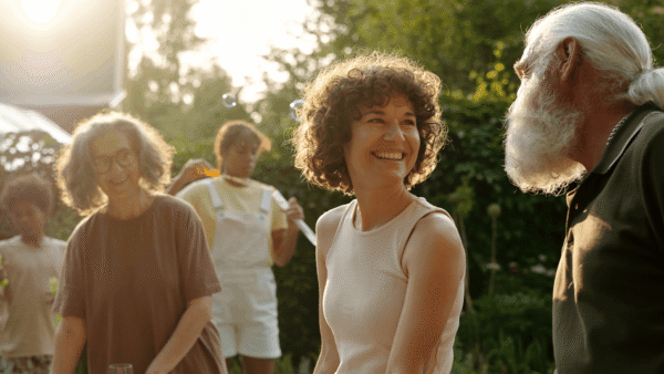 Adults of different generations smiling and talking together outdoors in warm afternoon light.