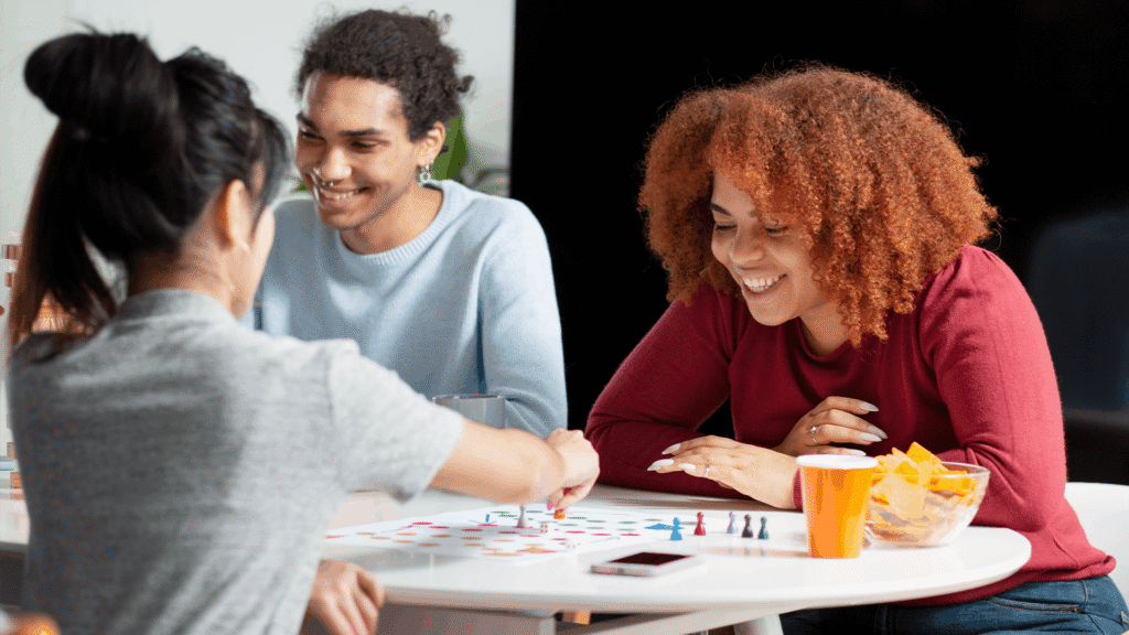 Intergenerational group smiling and playing a board game together at a table.