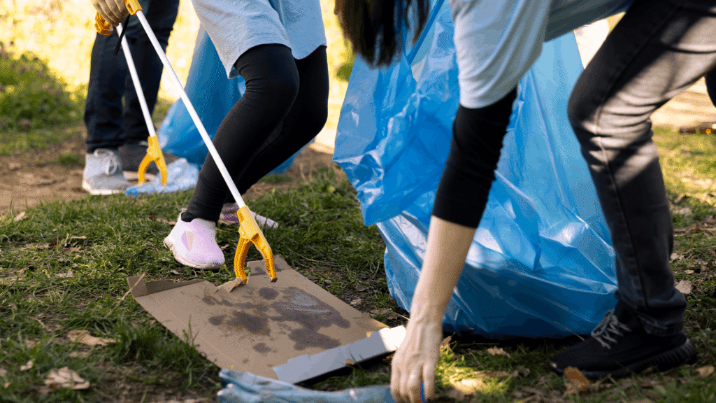 Youth group participating in a local summer service project by picking up trash in a park.