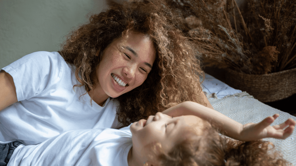 Parent and child lying together and smiling in a relaxed, affectionate moment at home