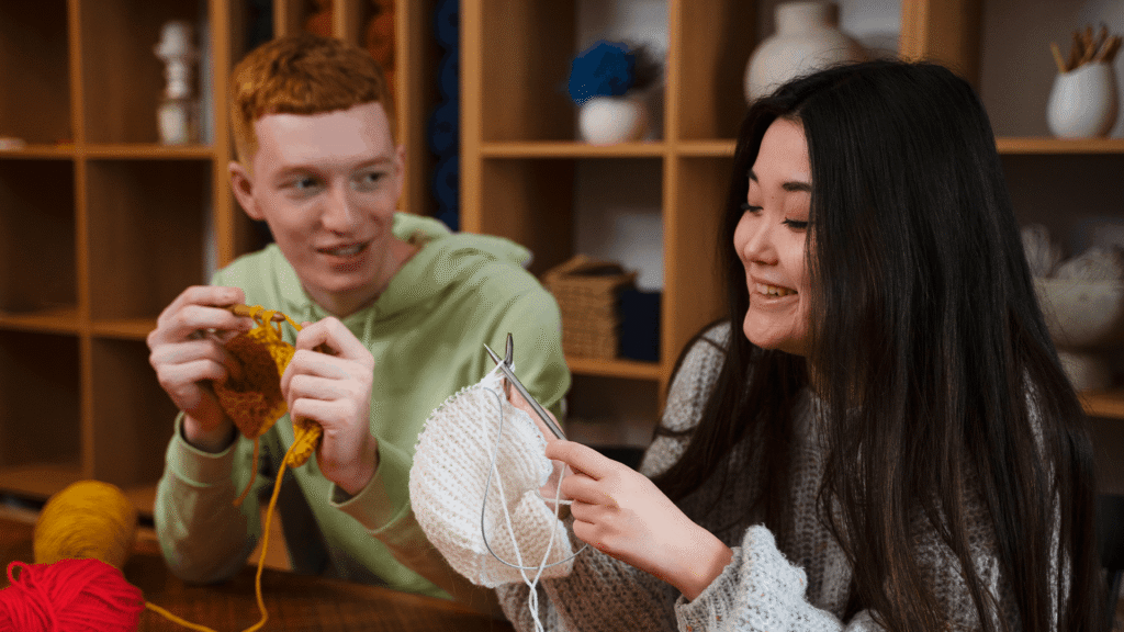 Two teenagers knitting together during a youth activity, illustrating accessible and inclusive ways to participate in youth ministry.