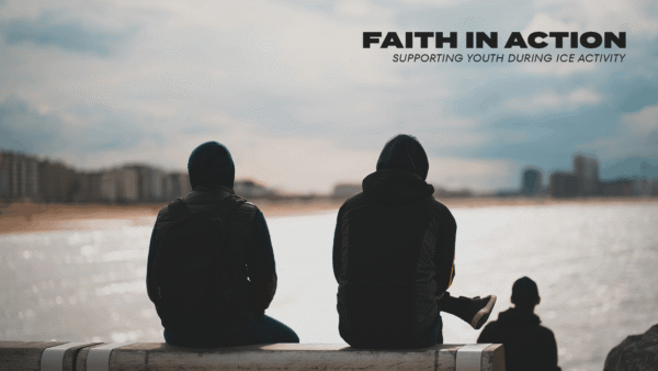 Two people sit side by side on a bench overlooking a calm waterfront under a cloudy sky, facing the horizon together.