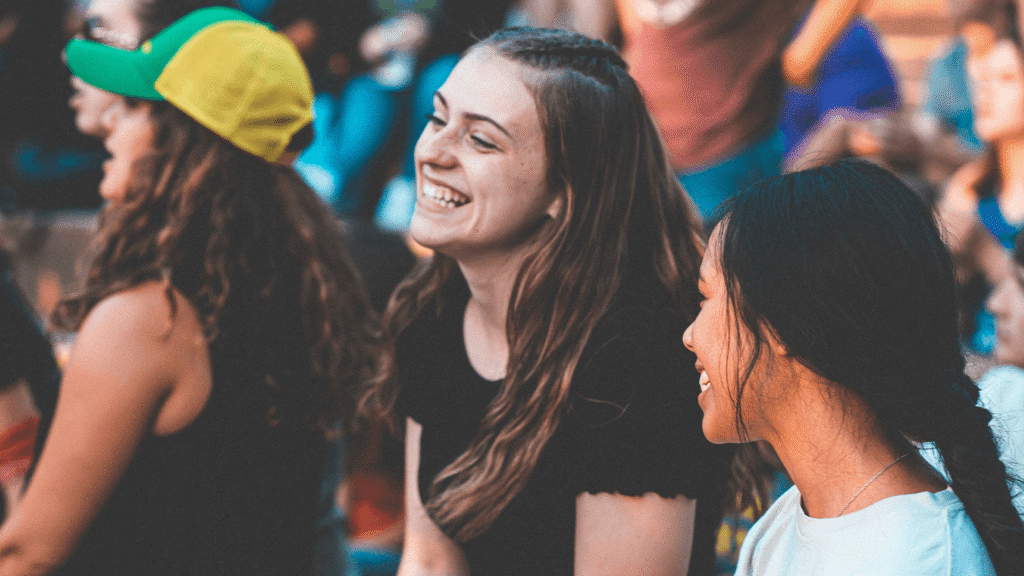 Teenagers smile and laugh together during an outdoor gathering.